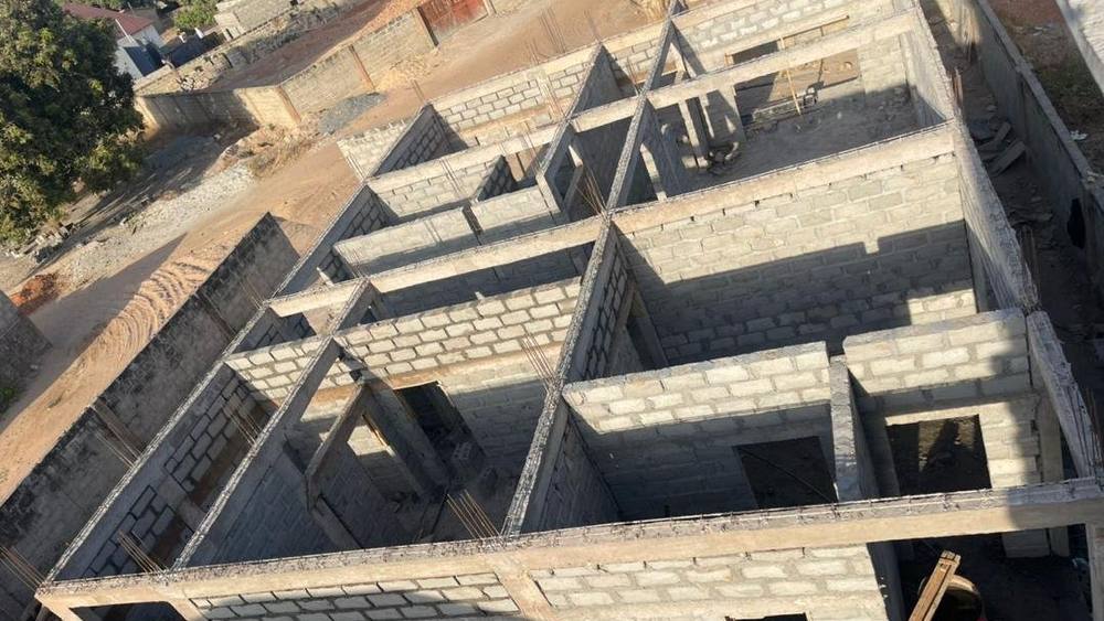 Looking down over the ground-floor blockwork at Jabang, the room divisions laid out and the concrete ring beam cast along the tops of the walls.