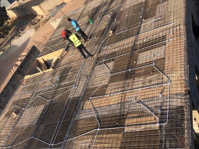 Steel reinforcement and service conduit laid across the first-floor slab, above the completed ground floor, before the concrete pour.