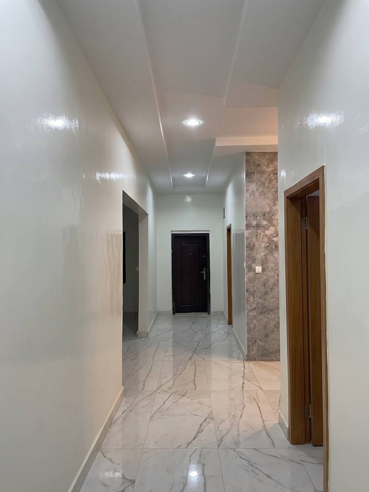The main hallway at Jalambang, floored in large-format marble tiling, with one pier clad in matching stone.