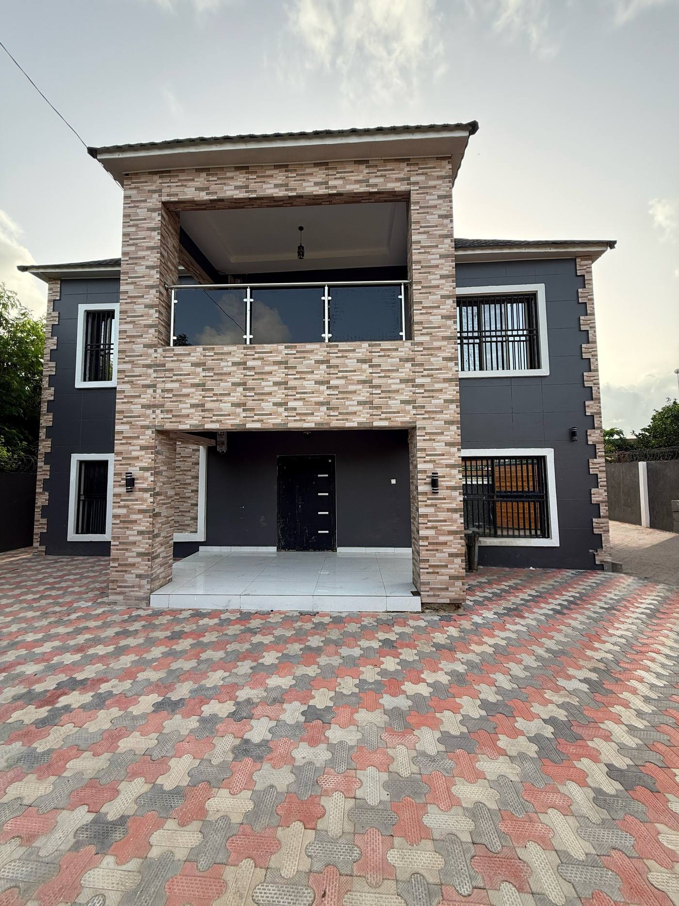 The front facade of the completed two-storey Kololi residence, with a stone-clad entrance bay rising through both floors.